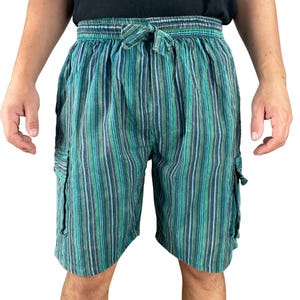 Puede incluir: Pantalones cortos a rayas verdes y azules con cintura con cordón y dos bolsillos cargo. Los pantalones cortos tienen rayas verticales en tonos de verde, azul y blanco. Los pantalones cortos están hechos de tela ligera.
