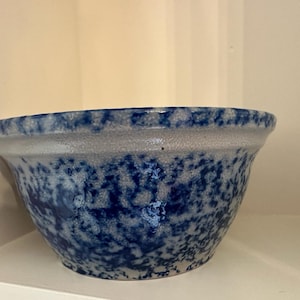 Puede incluir: Un tazón mezclador de cerámica grande, azul y blanco con un glaseado moteado. El tazón es redondo y tiene un borde ancho.