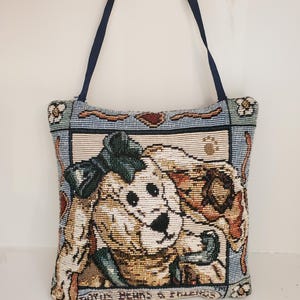 May include: A square tapestry tote bag featuring a woven illustration of a dog with a green bow, framed by a decorative border with floral accents and the text "BOYDS BEARS & FRIENDS" at the bottom, complete with dark blue fabric straps.
