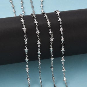 May include: Silver chain with star-shaped links. The chain is shown in multiple lengths.
