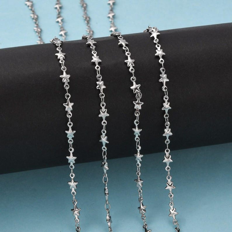 May include: Silver chain with star-shaped links. The chain is shown in multiple lengths.