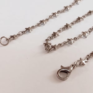 May include: A silver chain necklace with a star-shaped link design. The necklace has a lobster clasp closure.
