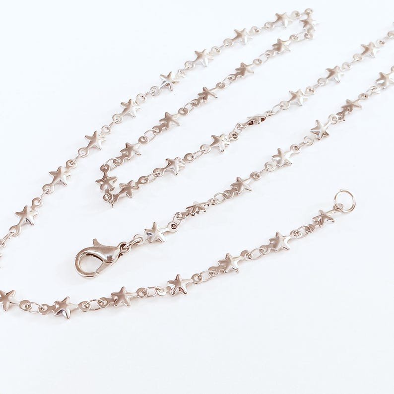 May include: A silver chain necklace with star-shaped links. The necklace is approximately 18 inches long and has a lobster claw clasp.