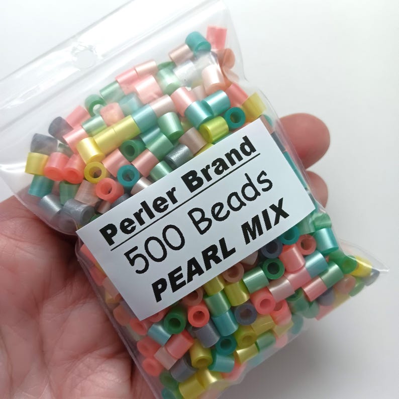 Puede incluir: Una bolsa de pl&aacute;stico transparente llena de cuentas Perler Brand. La etiqueta dice "Perler Brand 500 Beads PEARL MIX". Las cuentas cil&iacute;ndricas son de colores pastel: rosa, amarillo, verde y azul. Perfectas para manualidades.