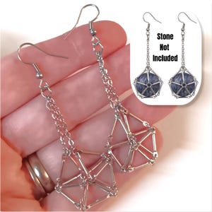 May include: Silver geometric cage earrings with a chain drop. The earrings are shown on a hand, and the text "Stone Not Included" is visible in the image.