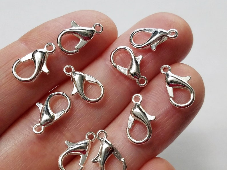 May include: Ten silver-toned lobster clasps, a type of fastener used in jewelry making.