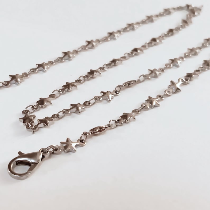 May include: A silver chain necklace with star-shaped links. The chain has a lobster clasp closure.