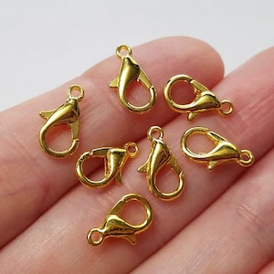 May include: Seven gold-toned metal lobster clasps, commonly used for jewelry making and crafting.