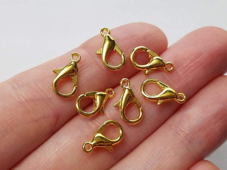 May include: Seven gold-toned metal lobster clasps, commonly used for jewelry making and crafting.
