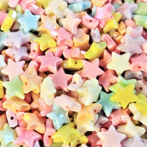 K&ouml;nnte beinhalten: Eine gro&szlig;e Auswahl an pastellfarbenen sternf&ouml;rmigen Perlen. Die Perlen sind aus Glas und haben eine leicht schimmernde Oberfl&auml;che.