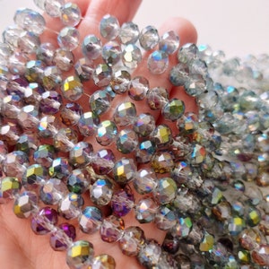 May include: A strand of iridescent glass beads with a faceted finish. The beads are a mix of light blue, purple, and green colors.