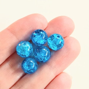 May include: Six round, blue glass beads with a sparkly, crackled finish. The beads are approximately 1 inch in diameter.