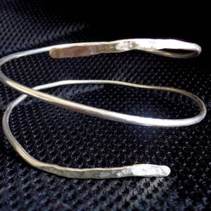 May include: A silver double-wrap bangle bracelet with a hammered finish.