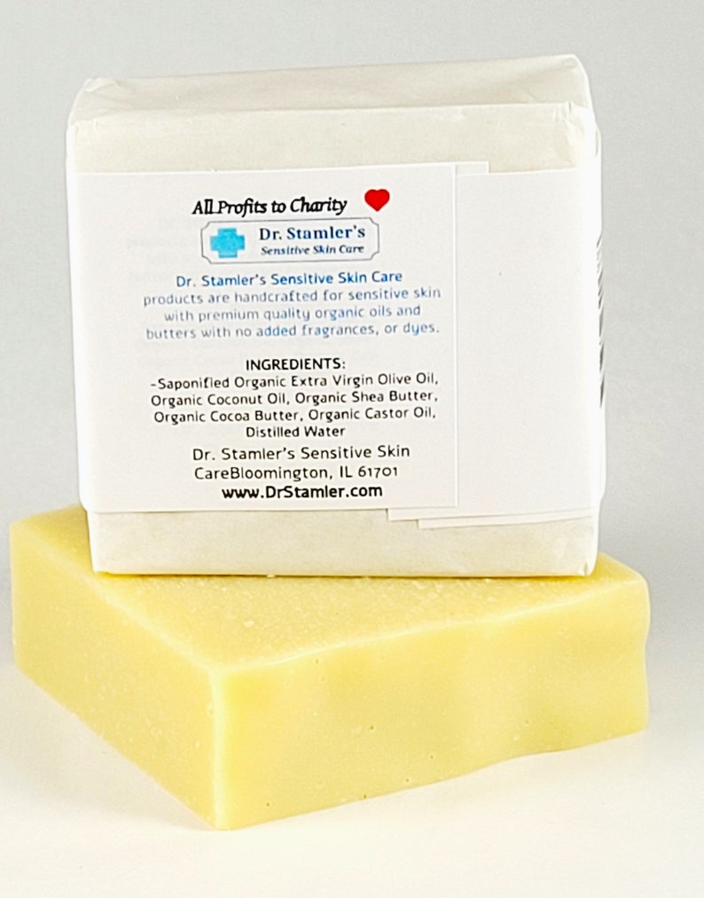 May include: A white bar of soap with a label that reads "All Profits to Charity" and "Dr. Stamler's Sensitive Skin Care". The label lists the ingredients, which include organic extra virgin olive oil, organic coconut oil, organic shea butter, organic cocoa butter, organic castor oil, and distilled water. The soap is handcrafted for sensitive skin and is made with premium quality organic oils and butters. The soap is packaged in a white box.