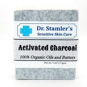 May include: A gray, rectangular bar of soap with white labels. The top label reads "Dr. Stamler's Sensitive Skin Care" with a blue cross symbol. The bottom label says "Activated Charcoal 100% Organic Oils and Butters". Net weight is 4 oz.