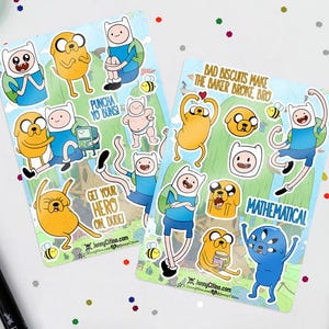 May include: Two Adventure Time sticker sheets featuring Finn and Jake characters in various poses. One sheet includes the text "PUNCHA YO BUNSI" and "GET YOUR HERO ON DUDE!". The other sheet has "BAD BISCUITS MAKE THE BAKER BROKE, BRO" and "MATHEMATICAL".