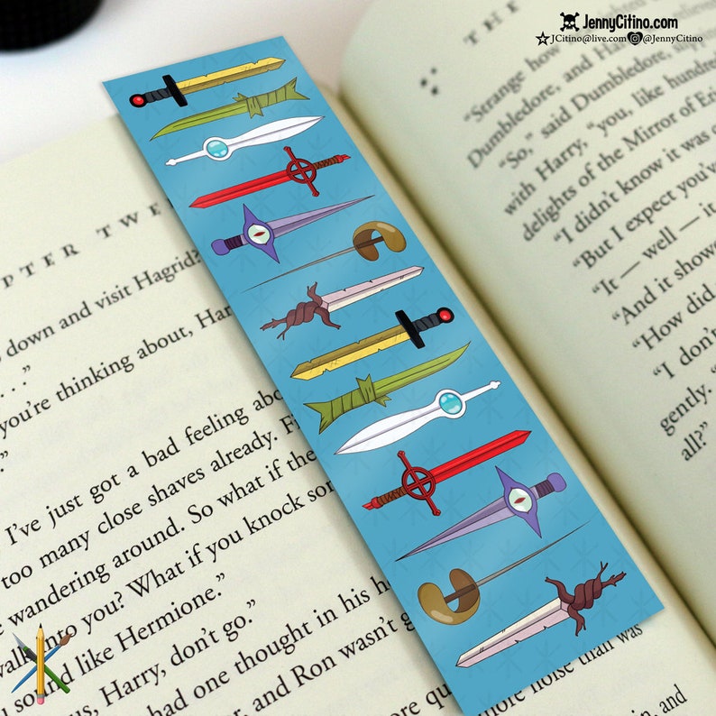 May include: A blue bookmark featuring various cartoon sword designs. The swords are in different colors, including yellow, green, red, and white. The bookmark is placed in a book with text visible. The text "JennyCitino.com" is at the top.