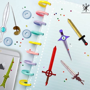 May include: A collection of colorful sword stickers on a blue and white notebook. The stickers feature different styles of swords, including a red sword with a cross, a purple sword with an eye, a yellow sword with a black handle, and a green sword with a brown handle.