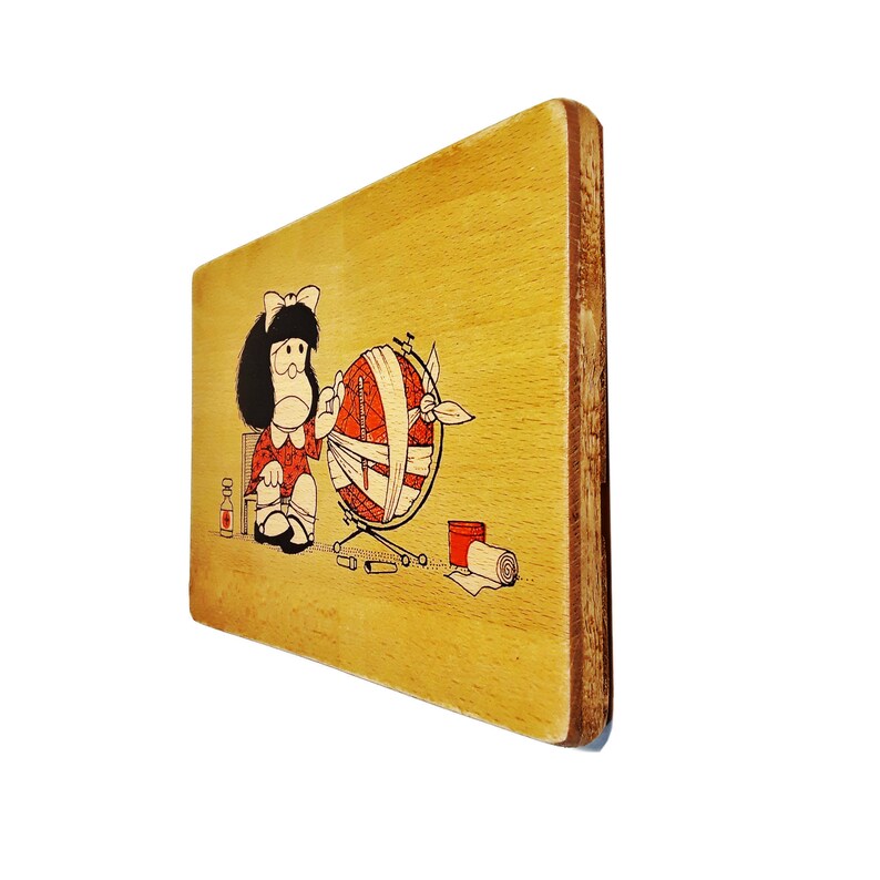May include: A wooden plaque with a cartoon illustration of a girl in a red dress holding a globe wrapped in bandages. The globe is on a stand with a small bottle and other items on the ground.