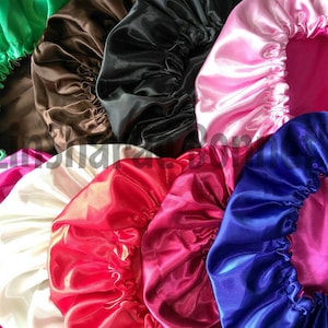 May include: Assortment of satin bonnets in various colors, including green, brown, black, pink, white, red, blue, and fuchsia. The bonnets are made of smooth, silky fabric and have a gathered, ruffled edge.
