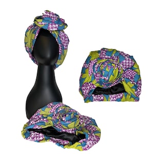 May include: A purple, green, and blue patterned turban with a rose-shaped design. The turban is made of fabric and is worn on the head.