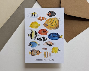 May include: A white card featuring watercolor illustrations of various tropical fish in vibrant colors. The card includes fish with stripes, spots, and unique patterns. The French text "Poissons Tropicaux" is printed at the bottom.