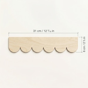 May include: A wooden shelf with a scalloped edge, measuring 12 3/16 inches long and 2 3/8 inches wide. The shelf is made of light-colored wood and has a simple, decorative design. The dimensions are also provided in centimeters.
