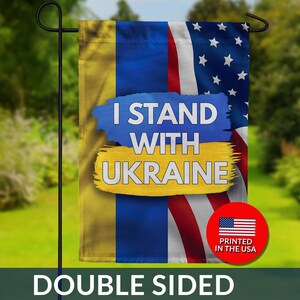May include: Double-sided garden flag with the text "I Stand With Ukraine" over a background that combines the Ukrainian and American flags. A red circle with the American flag and "Printed in the USA" is in the lower right corner.