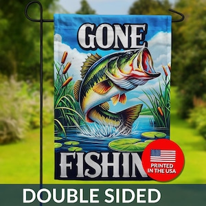 May include: Double-sided garden flag with a vibrant illustration of a largemouth bass leaping from water. The flag features the text "GONE FISHIN" in white block letters against a blue sky background. Includes a red circle with the American flag and "PRINTED IN THE USA".