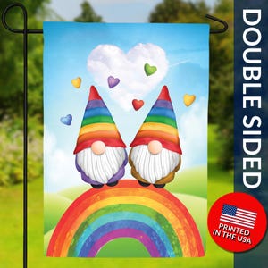 May include: Double-sided garden flag featuring two gnomes with rainbow hats and beards, standing on a rainbow. The background includes a heart-shaped cloud, colorful hearts, and the text "PRINTED IN THE USA".