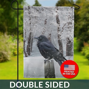 May include: Double-sided garden flag featuring a black crow perched on a wooden post. The background shows a snowy forest scene. The flag has the text "DOUBLE SIDED" and a "PRINTED IN THE USA" seal.