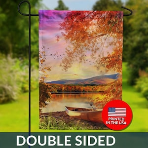 May include: Double-sided garden flag featuring a scenic autumn landscape with a lake, mountains, and a canoe. The flag displays vibrant colors of red, orange, and purple, with the text "DOUBLE SIDED". Includes a "PRINTED IN THE USA" graphic.