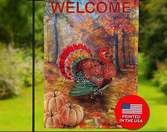 May include: Double-sided garden flag with a turkey, pumpkins, and the word "WELCOME" against a fall forest backdrop. The flag has a red, orange, and green turkey with a vibrant tail. The flag is printed in the USA.