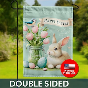 May include: Double-sided Easter garden flag featuring a white bunny, pink tulips in a jar, and blue eggs. A blue bird and a banner with "Happy Easter" are also displayed. The flag is printed in the USA.