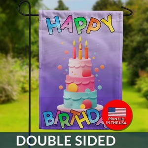 May include: Double-sided garden flag with a birthday cake design. The flag features a multi-tiered cake with lit candles, colorful text that reads "HAPPY BIRTHDAY", and a "PRINTED IN THE USA" emblem. The flag is displayed outdoors.