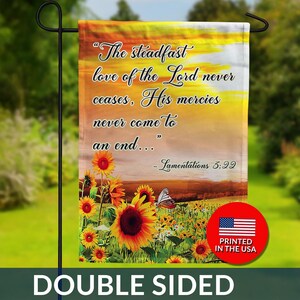 May include: Double-sided garden flag with a sunset background and sunflowers. The flag features the quote "The steadfast love of the Lord never ceases, His mercies never come to an end..." from Lamentations 3:22. Includes a "Printed in the USA" logo.