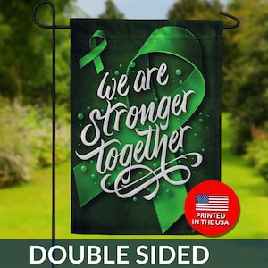 May include: Double-sided garden flag with a dark green background and a large green ribbon design. The words "We are Stronger Together" are written in white script. A smaller green ribbon and a red circle with the US flag are also visible.
