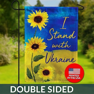 May include: A double-sided garden flag with a blue and yellow background, featuring sunflowers and the text "I Stand with Ukraine." A red circle with the US flag and "Printed in the USA" is in the lower right corner.