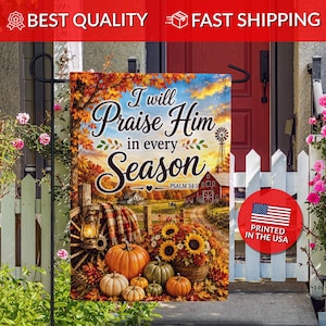 May include: A rectangular garden flag featuring a fall landscape with pumpkins, sunflowers, a wooden wagon wheel, and a red barn. The text reads I will Praise Him in every Season and Psalm 34:1. The scene includes autumn foliage and a sunset sky.