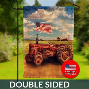 May include: Double-sided garden flag featuring a vintage red tractor in a field with an American flag waving in the wind. The background includes a red barn, windmill, and a cloudy blue sky. The flag has the text "DOUBLE SIDED".