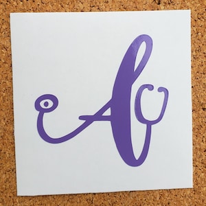 May include: A white square sticker featuring a purple design. The design is a stylized letter "A" with a stethoscope incorporated into the design. The stethoscope is on the right side of the letter.