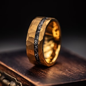 Men's Gold hammered wedding ring with silver meteorite inlay standing upright on walnut ring box