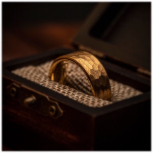 Yellow gold ring with hammered finish in walnut ring box between burlap cushions