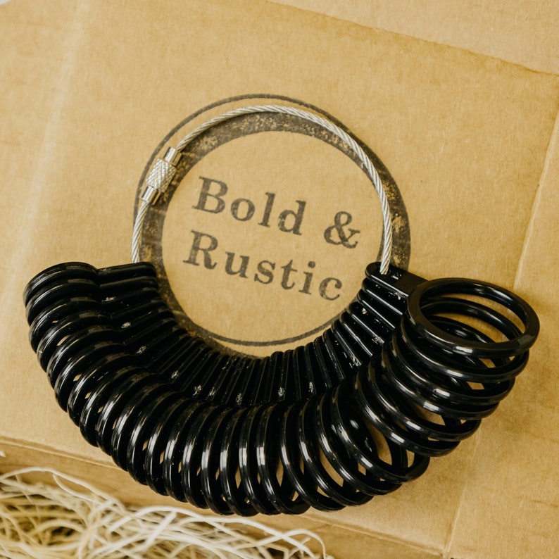 May include: A black ring sizer with a silver chain and a tag that says "Bold & Rustic".
