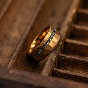 Men's Gold Tungsten wedding band with hammered finish and silver meteorite inlay leaning to the side in a wooden box