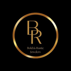 May include: A gold logo on a black backdrop. The logo shows the letters "B" and "R" in gold, intertwined within a gold circle. Below the letters, the text reads "Bold & Rustic Jewelers."