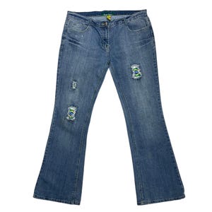 May include: Blue denim jeans with distressed details and colourful patches. The jeans have a wide leg style.