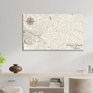 May include: A vintage-style map print of Arroyo Grande, California. The map features brown lines representing roads and waterways, a compass rose, and the city name in a brown script font.