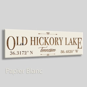 May include: A white wooden sign with brown text that reads "Old Hickory Lake, Tennessee, 36.3172° N, 86.4820° W".