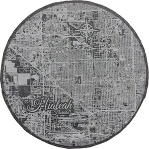 May include: A black and white map of Hialeah, Florida, printed on a round slate coaster. The map shows the city's streets and landmarks.